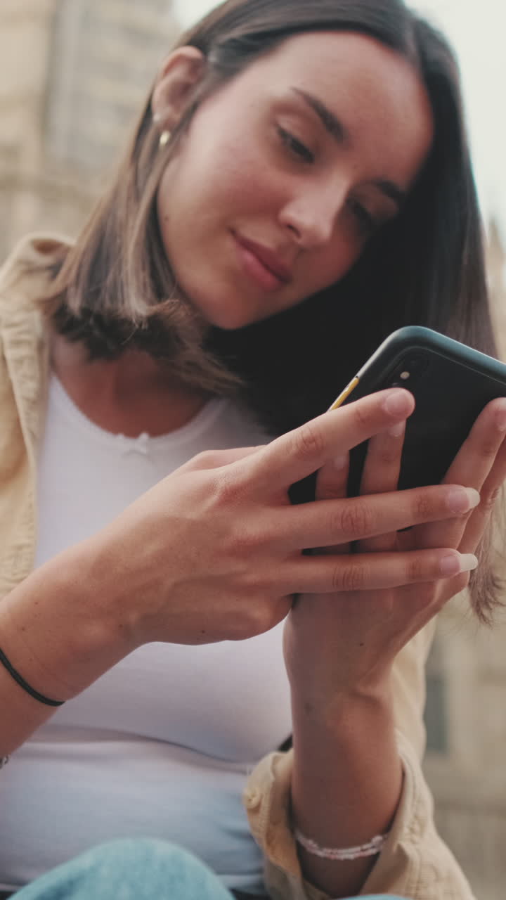 Giovane donna che utilizza uno smartphone all'aperto, scorrendo e digitando