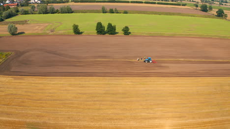 aerial view of drone flying above farmland with tractor on the field