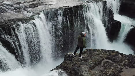 Majestätischer-Wasserfall-Im-Hochland-Von-Island-Luftpanorama,-Das-Einen-Einsamen-Mann-Zeigt,-Der-Oben-Auf-Einer-Klippe-Steht
