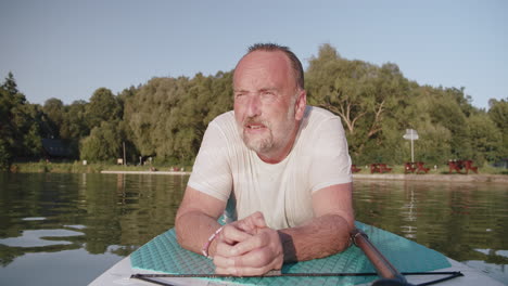 portrait of an elderly man relaxing on a paddleboard