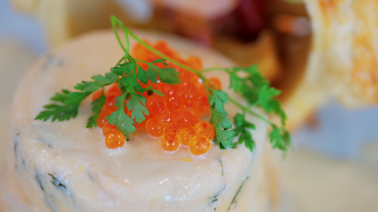 Close up of a fish mousse with salmon roe and puff pastry on a white plate at a restaurant