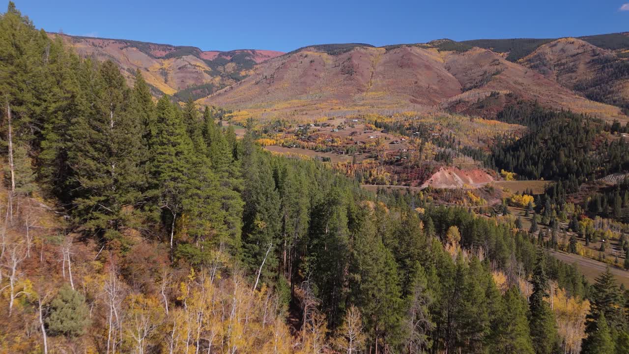 Low drone shot over hill to reveal Aspen mountain in autumn