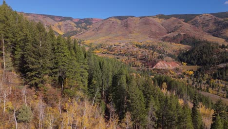 Low-drone-shot-over-hill-to-reveal-Aspen-mountain-in-autumn