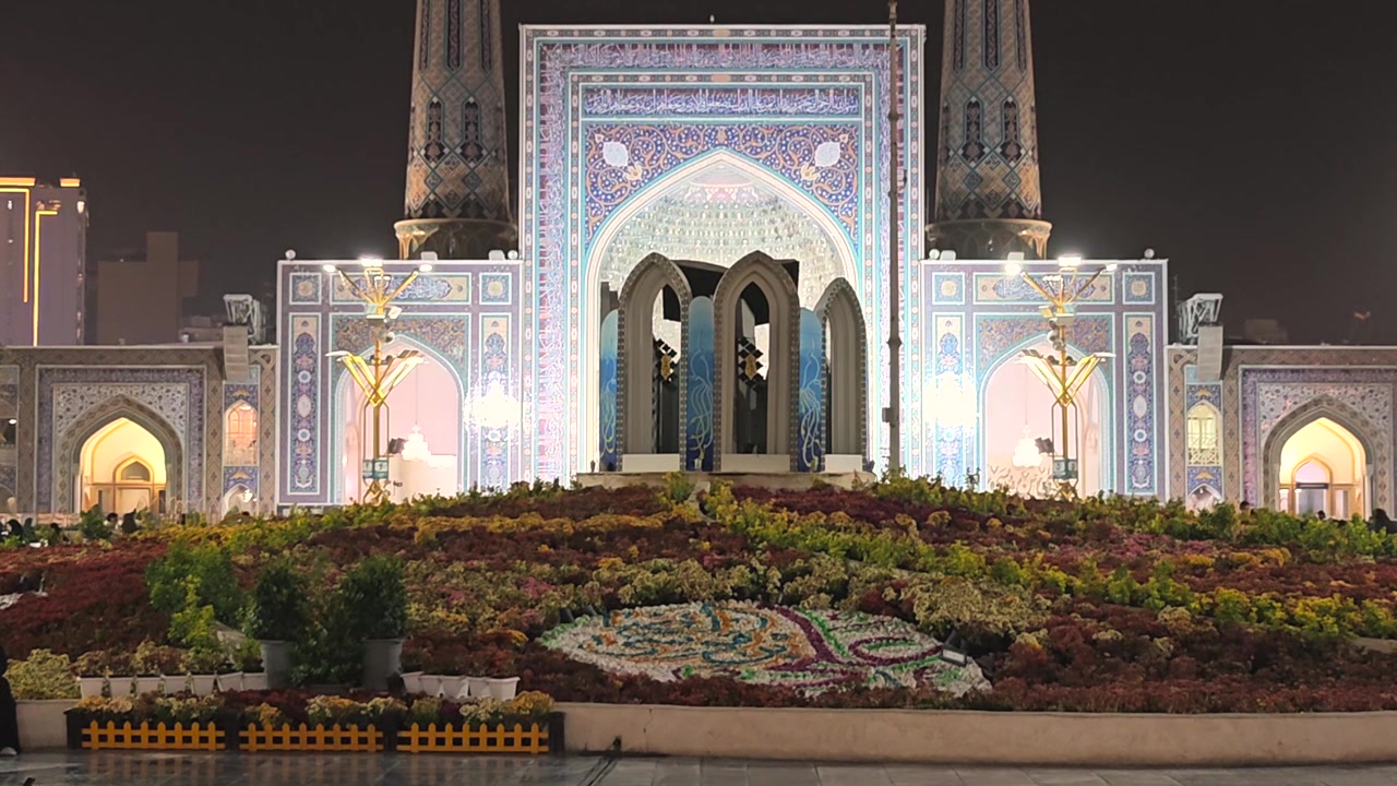 Illuminated Mosque Entrance With Vibrant Flower Bed at Night