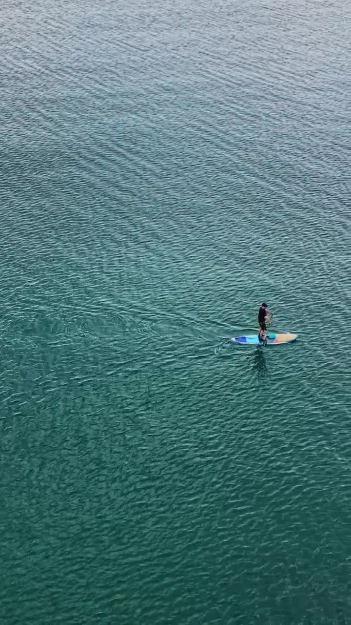 Persona che fa paddleboard in acque calme durante il giorno soleggiato