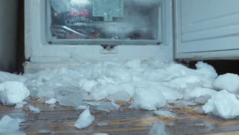 static view of wooden floor covered in ice from freezer with door open