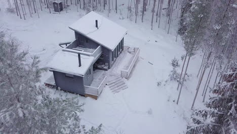 cabaña de invierno rural remota en medio del paisaje forestal en finlandia, disparo de drones