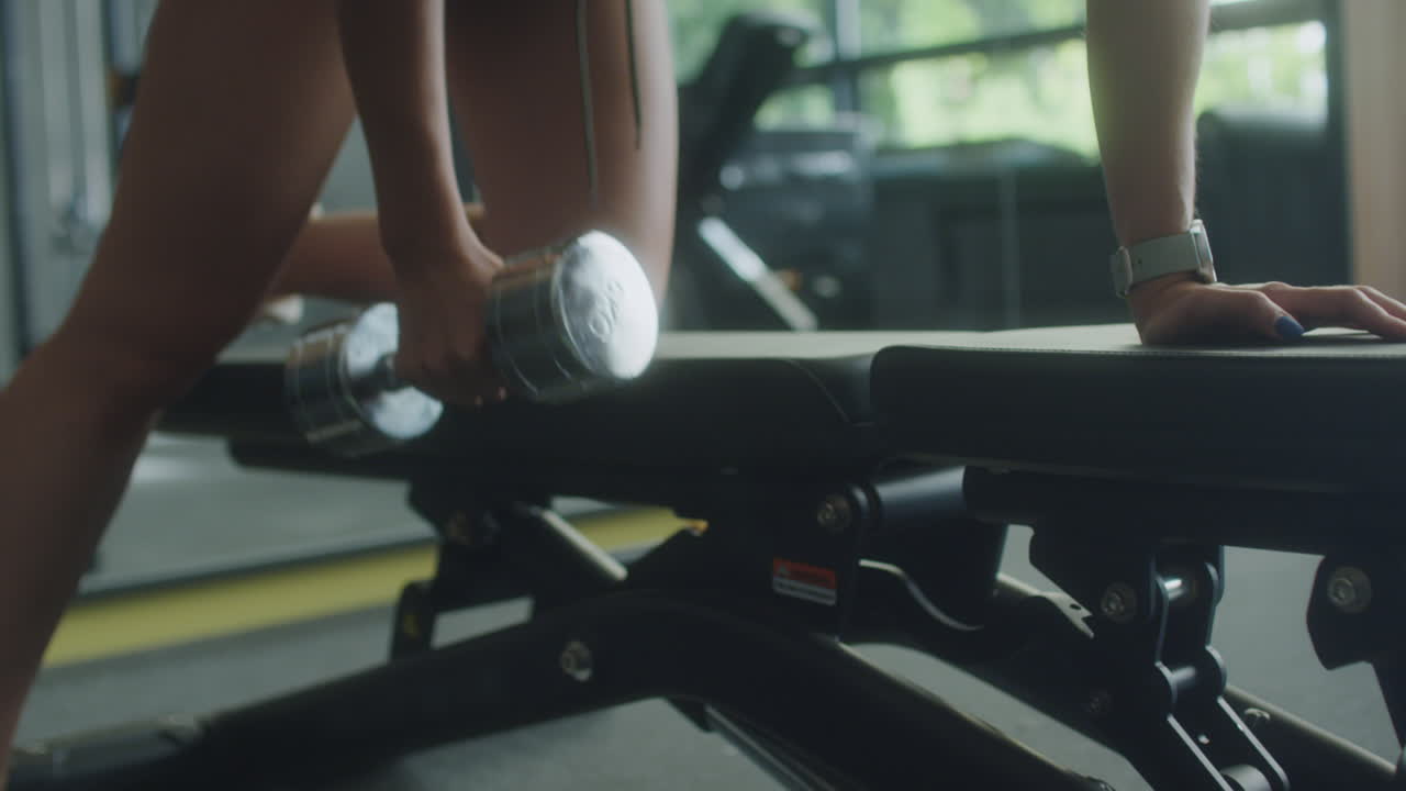 Donna che esegue rematore con manubri su panca in palestra