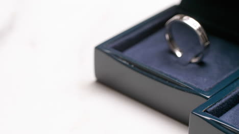 a close-up of a couple's engagement rings that is placed on a dark-blue, velvet-covered box