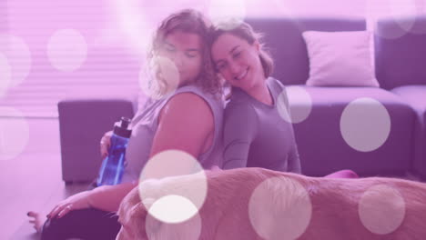 puntos de luz contra dos mujeres caucásicas jugando con su perro en casa