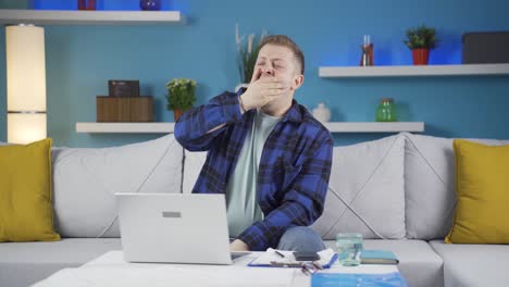 Home-office-worker-man-yawns-and-relaxes-at-the-camera.