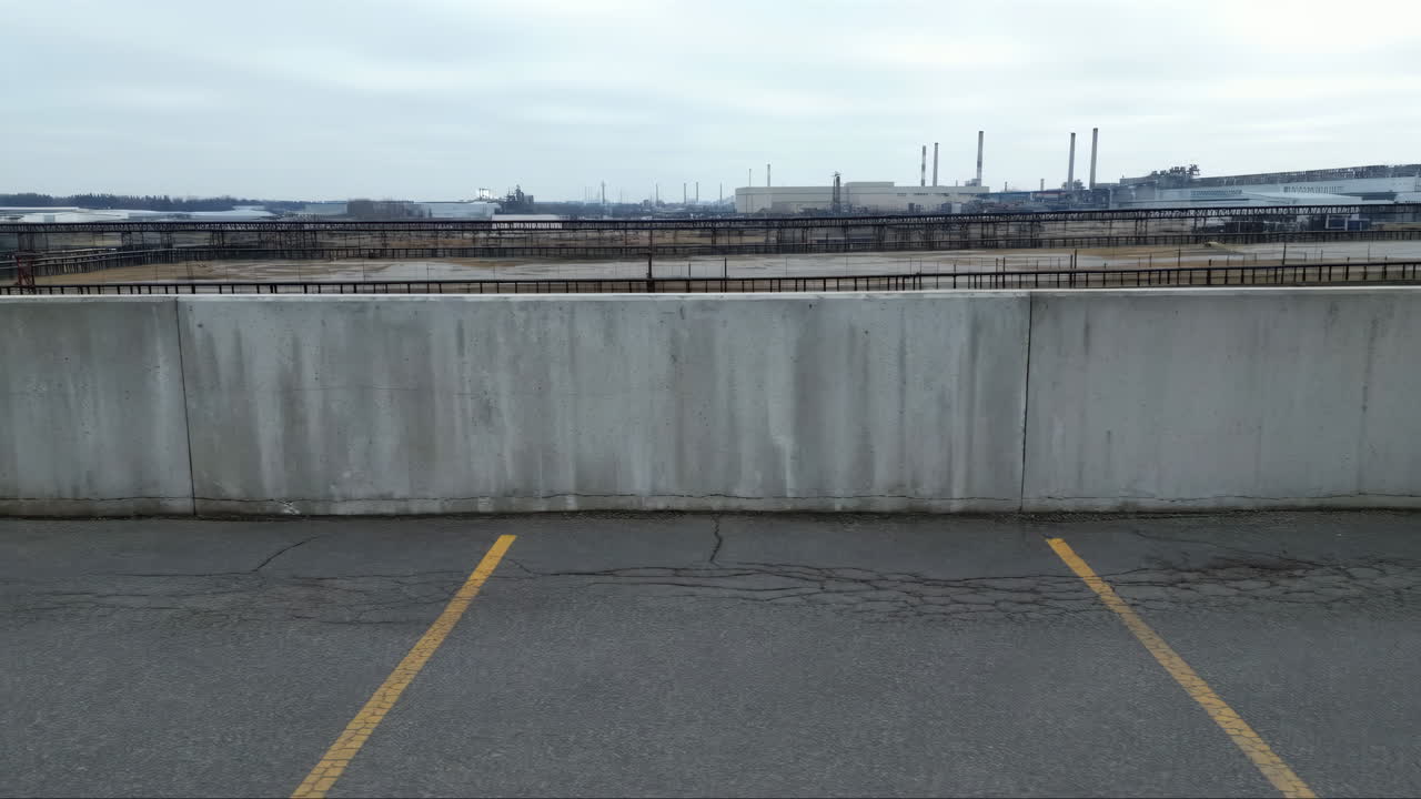 Industrial Complex Behind Concrete Barrier and Empty Parking Lot