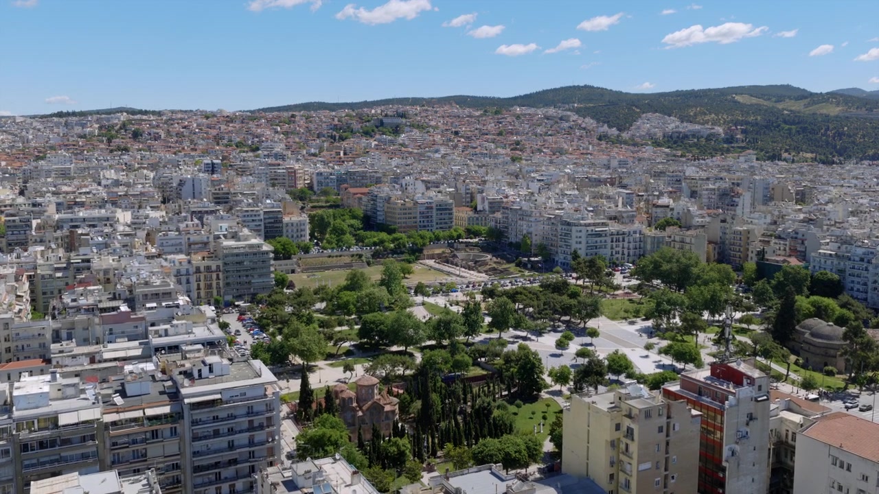 Veduta aerea del vivace centro città di Salonicco, che mostra tetti con architettura mista e verdi colline che si ergono sullo sfondo.