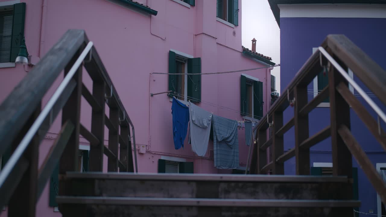 puente de madera que conduce a coloridas casas con ropa colgada en la isla de burano, venecia
