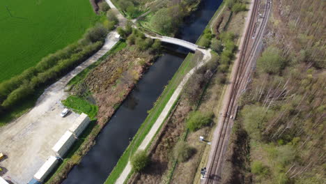 green and brown tree and blue canal, aerial view of train track and bridge in the north of the uk