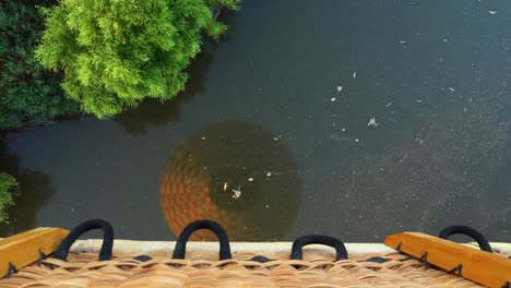 hot air balloon basket and envelope reflection overflying the river