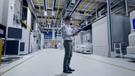 full body side view of an asian male professional worker standing with his tablet at factory digitalization, he raises his fist up with screaming goal