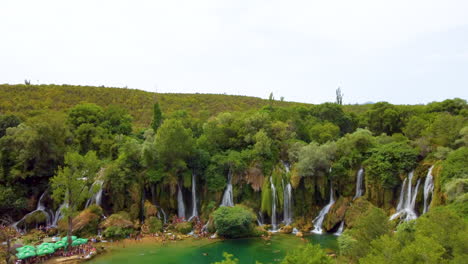 panorama of kravica waterfall with bright green trees during spring in bosnia and herzegovina. - aerial approach