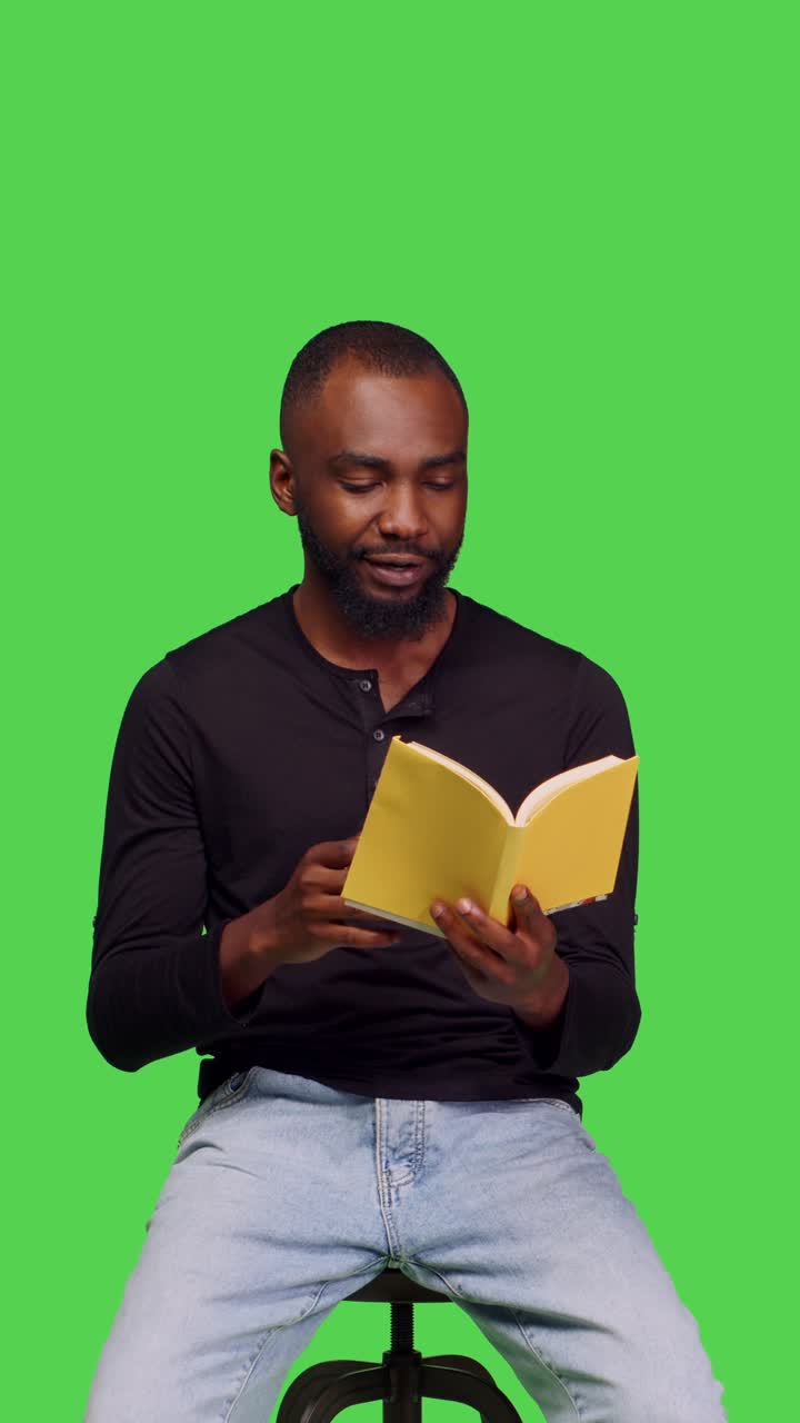 Vertical video: Front view of confident adult holding book to read pages on camera