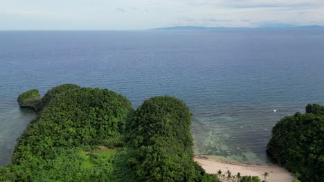 una vista aérea de una bahía serena en la isla de catanduanes, filipinas, que muestra la playa, las montañas cubiertas de árboles y el océano cristalino