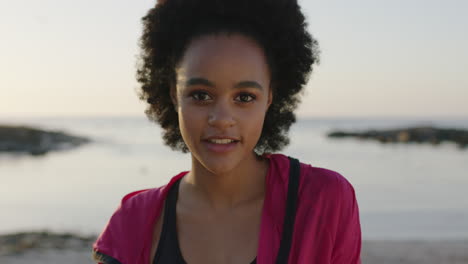 retrato de una joven atlética afroamericana sonriendo alegremente en una playa tranquila al atardecer