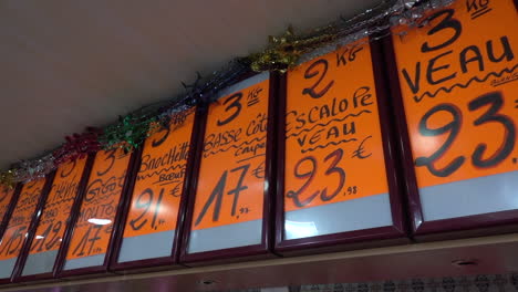 meat stall in a market with price tags shows above the head