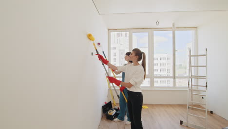 women painting a wall in a room