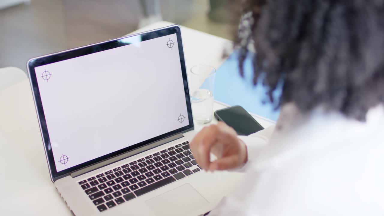 mujer de negocios casual biracial en la oficina haciendo llamada de video portátil, espacio de copia en la pantalla, cámara lenta