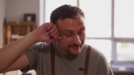 un trabajador cansado limpia el sudor de la frente en un pequeño taller