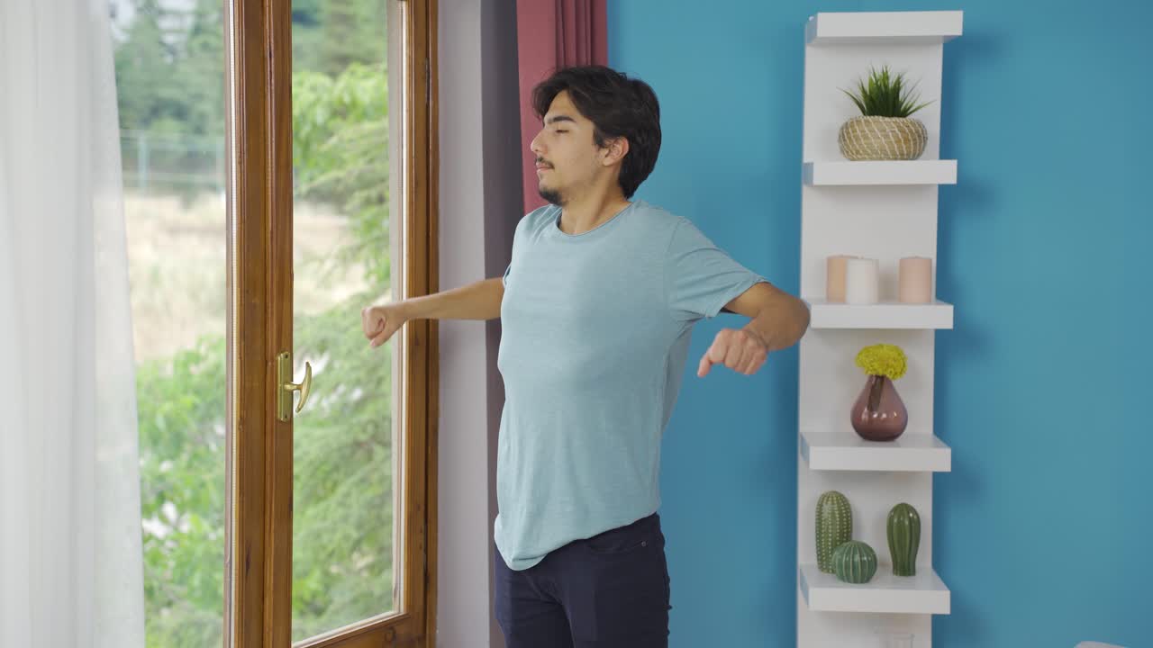 The man who opens the curtains yawns and relaxes.