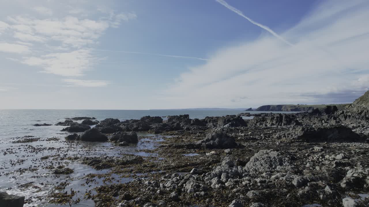 drone flying over rocks calm seas on a sunny day copper coast waterford ireland