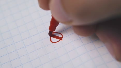 persona dibuja un círculo con un marcador rojo en papel a cuadros en blanco