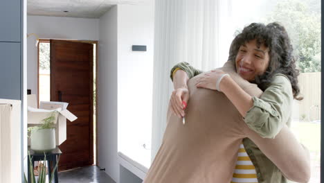 happy biracial couple embracing with cartons at new house, slow motion