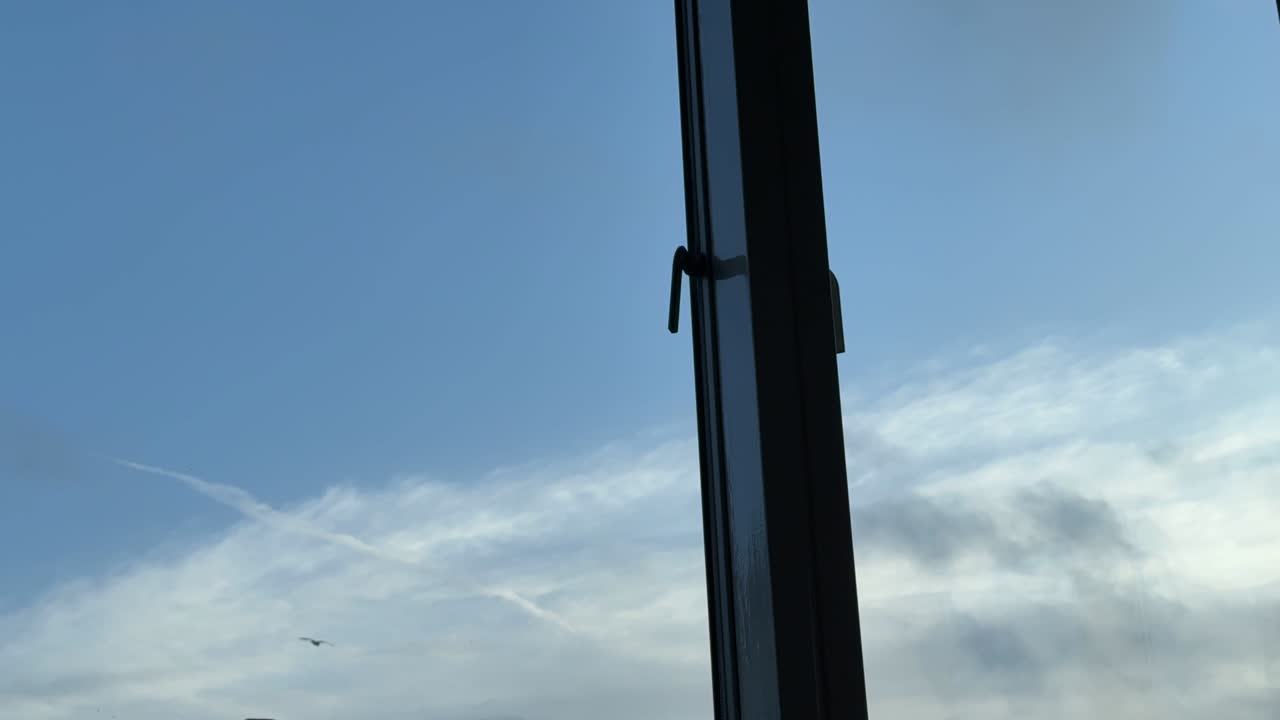 Timelapse of Clouds Moving Past Window Frame Against Blue Sky