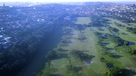 Drone-flying-over-the-Bluff-Golf-course-with-grosvernor-boys-high-school-in-the-back-over-moving-people-and-cars