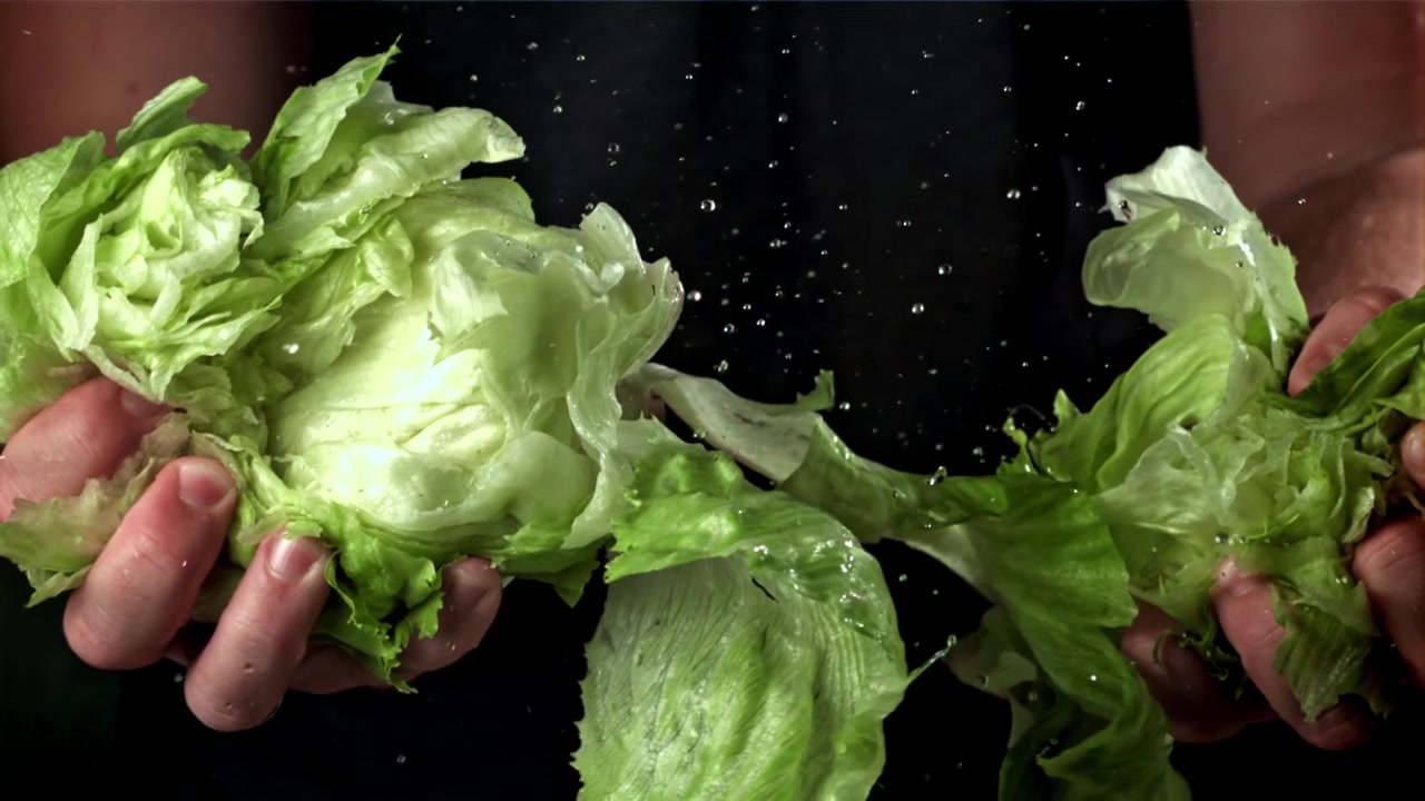 Water spat in slow motion op verse ijsbergsla