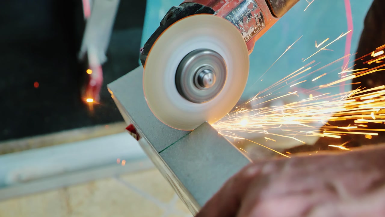 Industrial worker cutting metal profile with sparks, modern infrastructure
