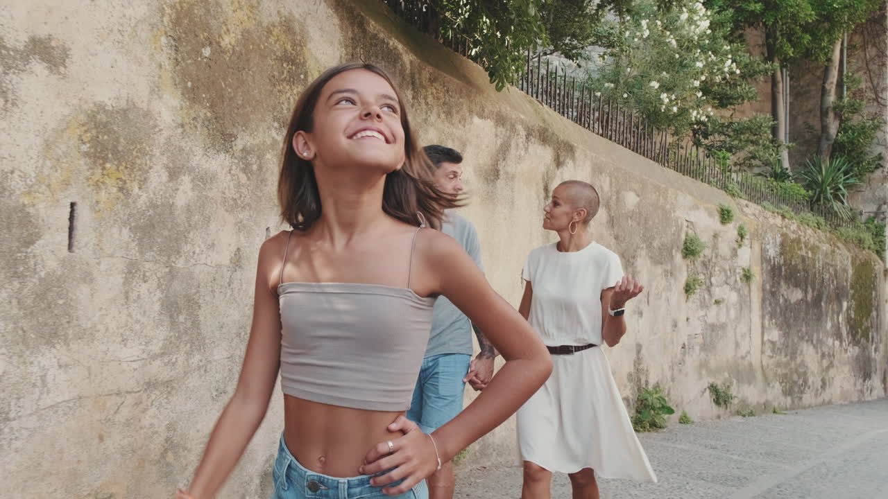 Happy Young Girl Points Up While Walking with Parents