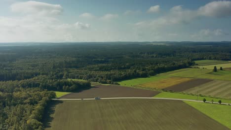 maravillosa amplia vista aérea sobre un paisaje de campos, bosques y una carretera rural colocada con coches de conducción, concepto para viajes idílicos