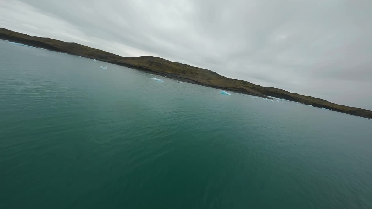 vuelo aéreo de drones fpv sobre icebergs a la deriva en una laguna glacial en la bahía de jokulsarlon, islandia