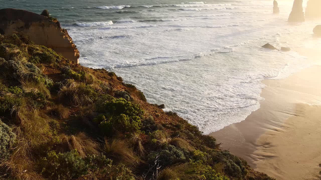 Waves crashing against cliffs and sandy beach