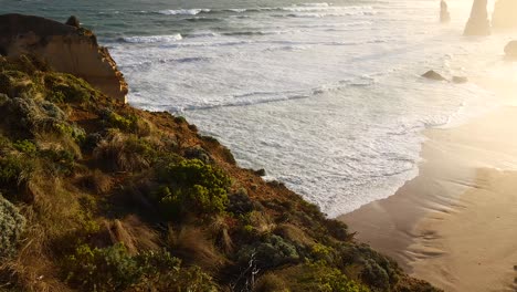 waves crashing against cliffs and sandy beach
