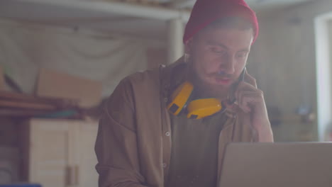 woodworker speaking on phone and working on laptop