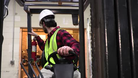 trabajador del almacén con un casco que opera una carretilla elevadora