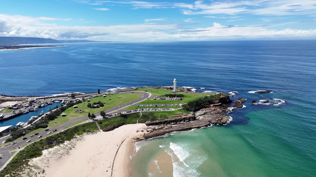 Aerial orbit over Wollongong Beach and rocky point with waves breaking along the coast
