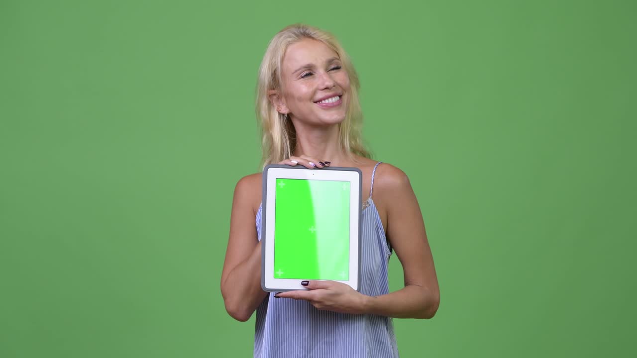 Young happy beautiful businesswoman thinking while showing digital tablet