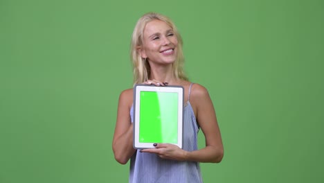 young happy beautiful businesswoman thinking while showing digital tablet