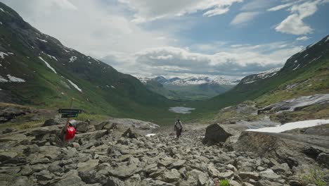 Los-Excursionistas-Exploran-Un-Valle-Pintoresco-Rodeado-De-Montañas-Cubiertas-De-Nieve-Bajo-Un-Cielo-Parcialmente-Nublado.