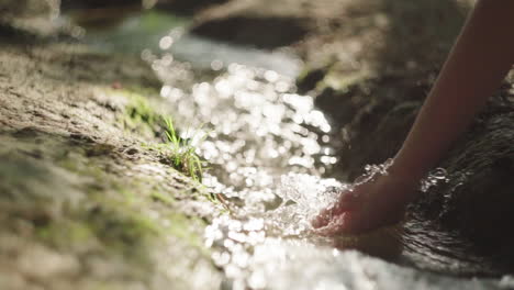 crop woman touching flowing water in river at night