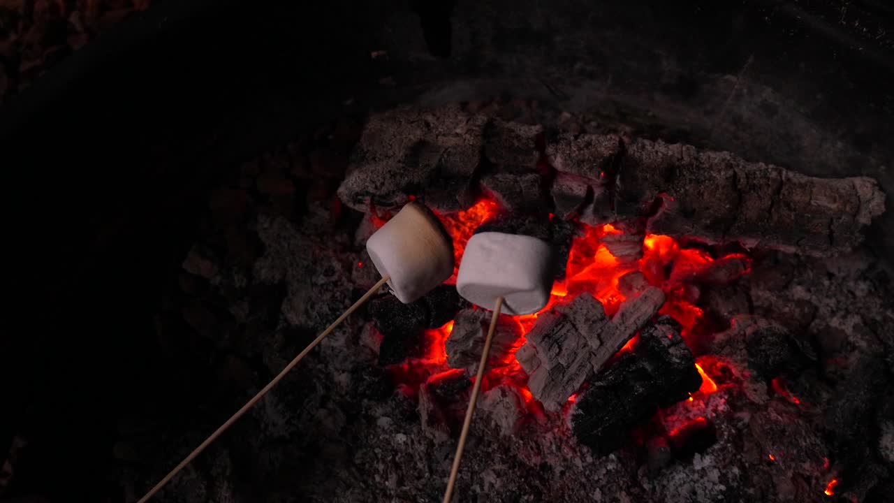 Assando marshmallows sobre brasas incandescentes em uma fogueira